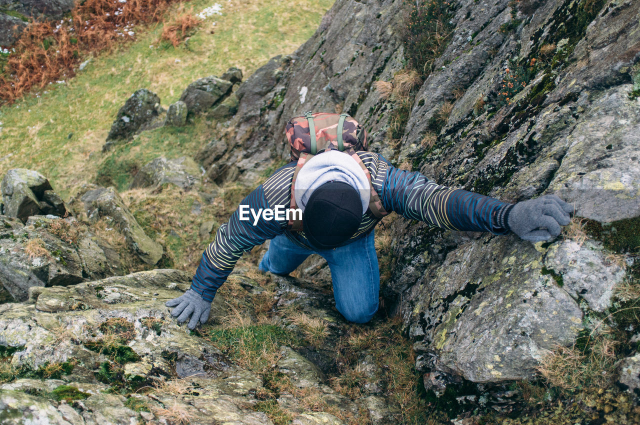 High angle view of young man climbing on the cliff