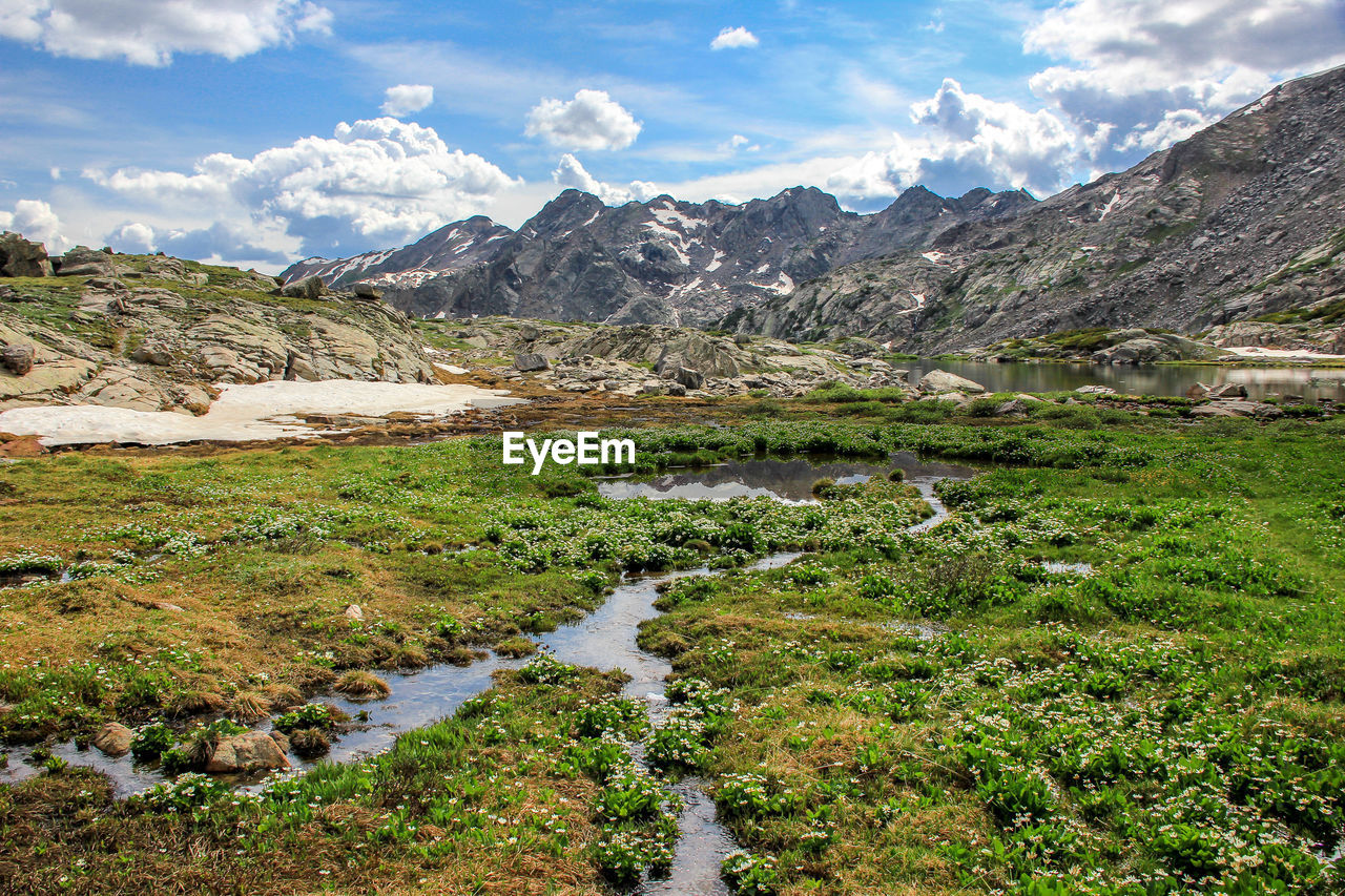 SCENIC VIEW OF STREAM BY MOUNTAINS AGAINST SKY