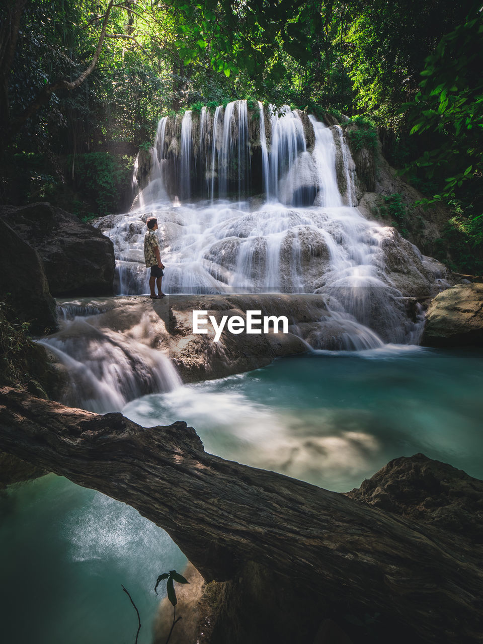 Solo traveler enjoy scenic waterfall, turquoise pond in forest. erawan fall, kanchanaburi, thailand.