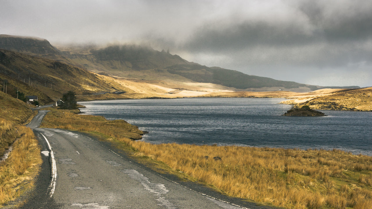 Scenic view of road by sea against sky