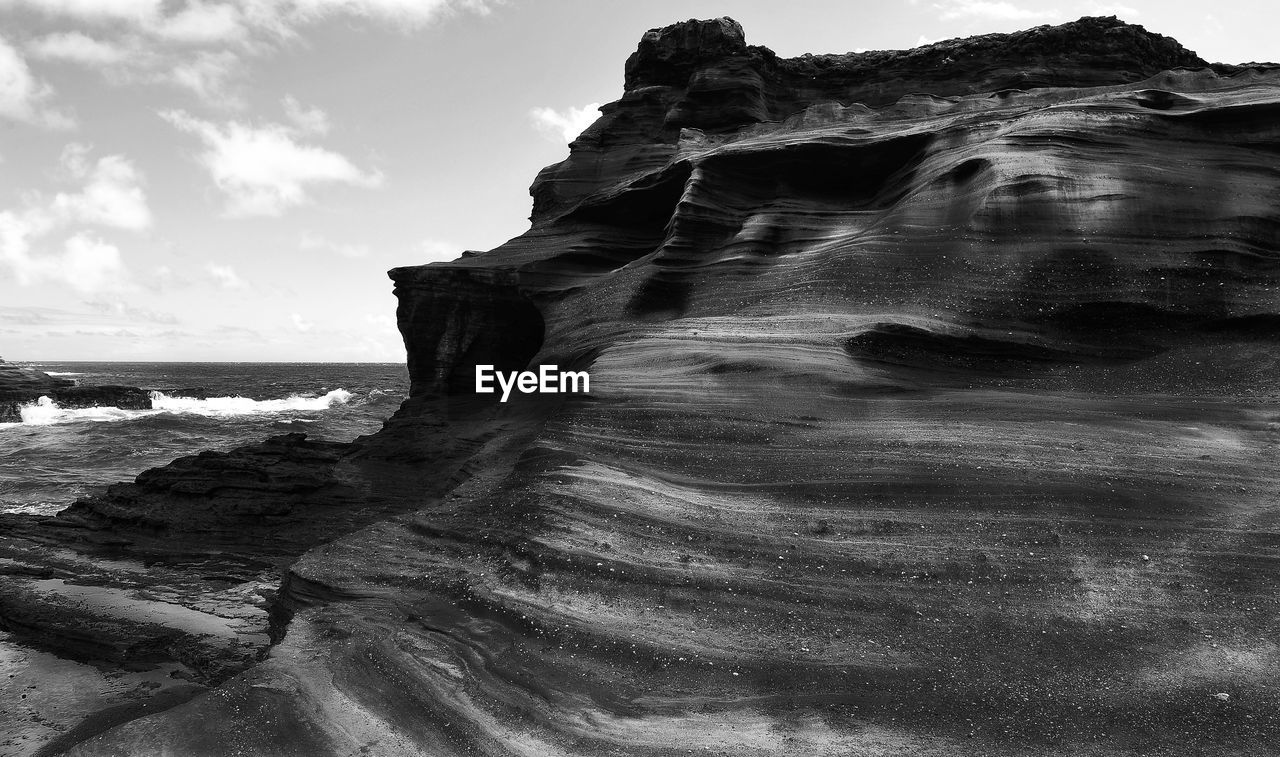 Close-up of rock formations at sea shore against sky