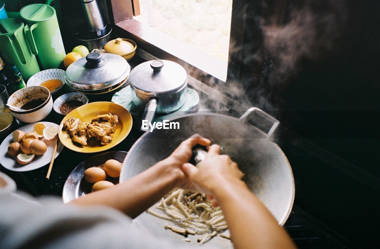 Cropped image of woman preparing food by window at kitchen