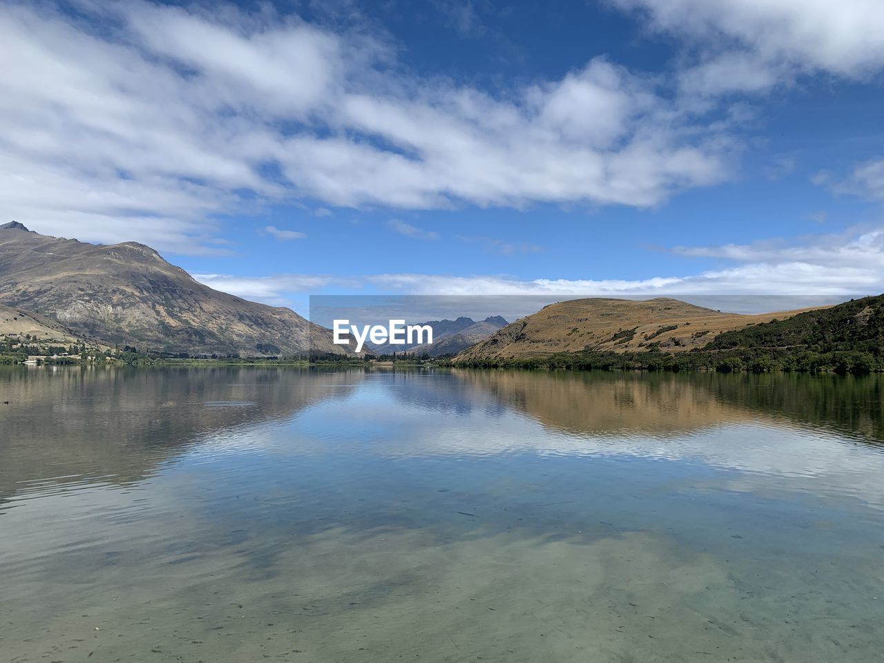 Scenic view of lake by mountains against sky