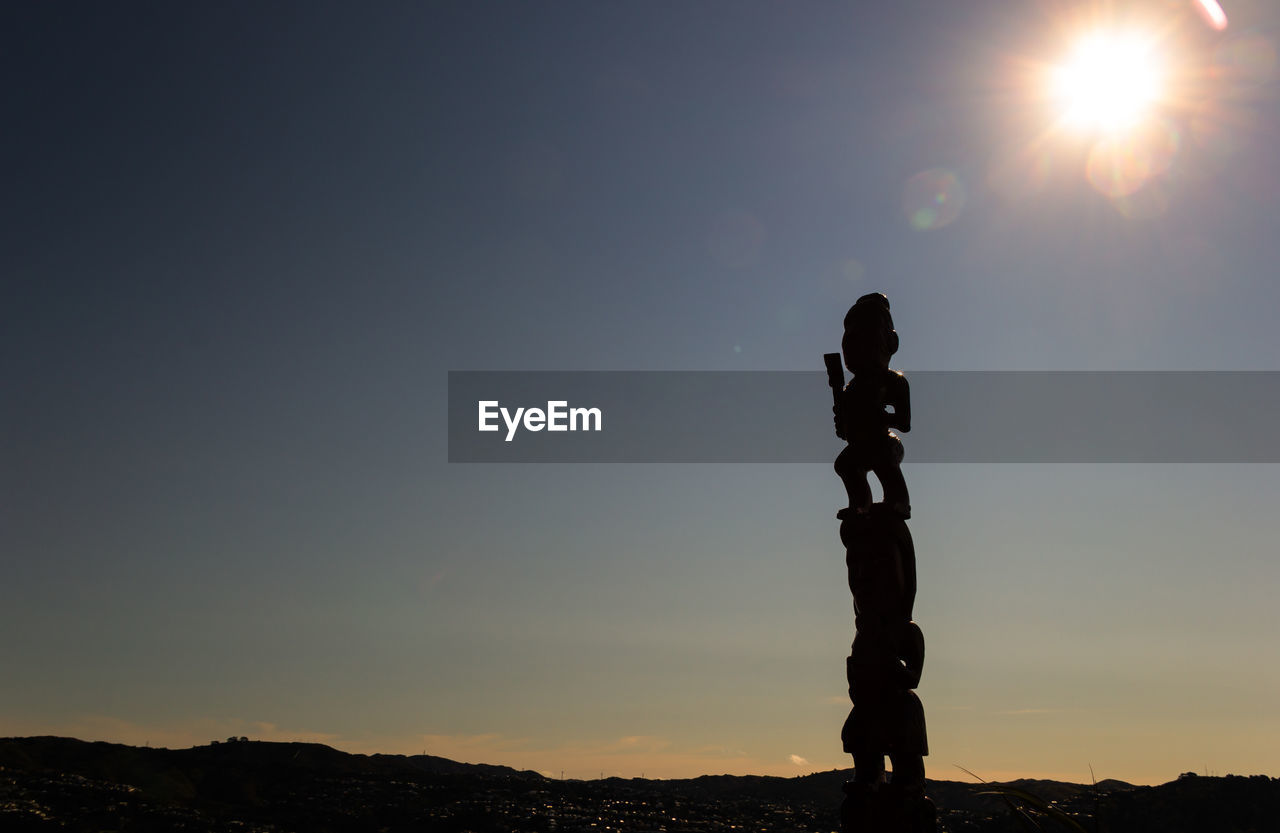 SILHOUETTE MAN STANDING AGAINST SUN DURING SUNSET