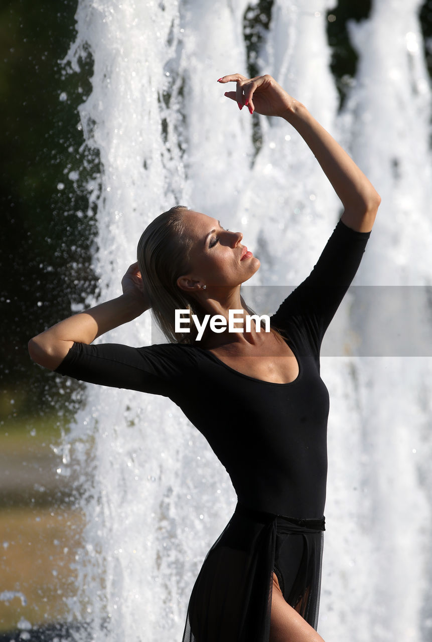 WOMAN STANDING IN WATER AT WATERFALL