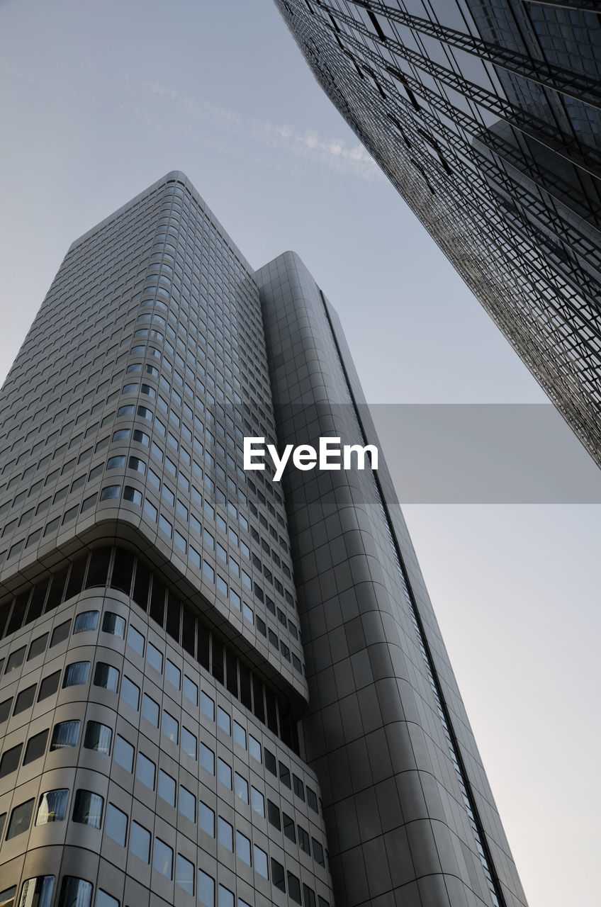 LOW ANGLE VIEW OF MODERN GLASS BUILDING AGAINST SKY