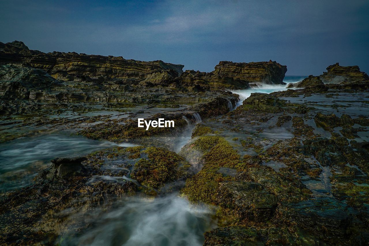 Scenic view of rocks in sea against sky