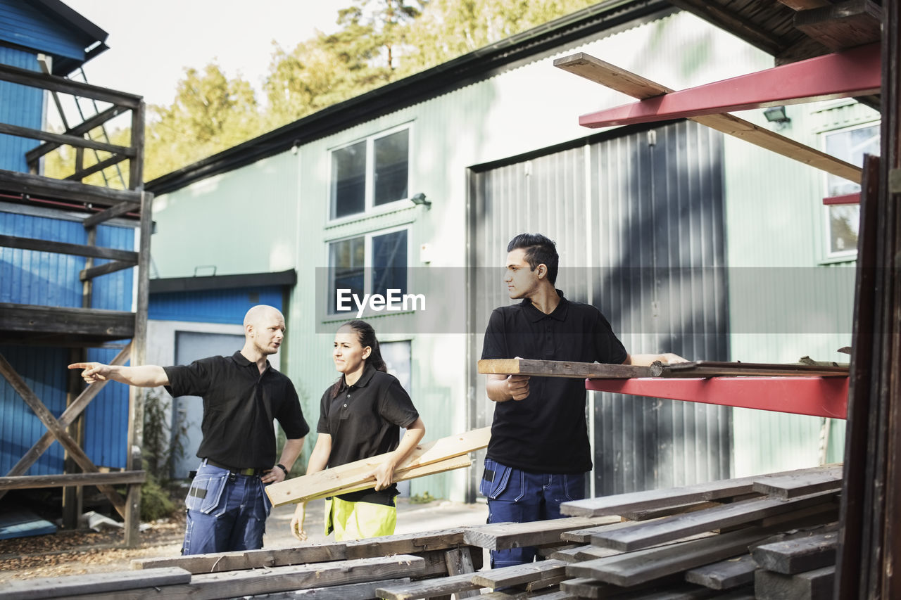 Carpentry teacher explaining students outside school