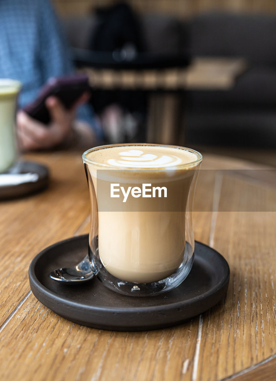 COFFEE CUP ON TABLE AGAINST CAFE