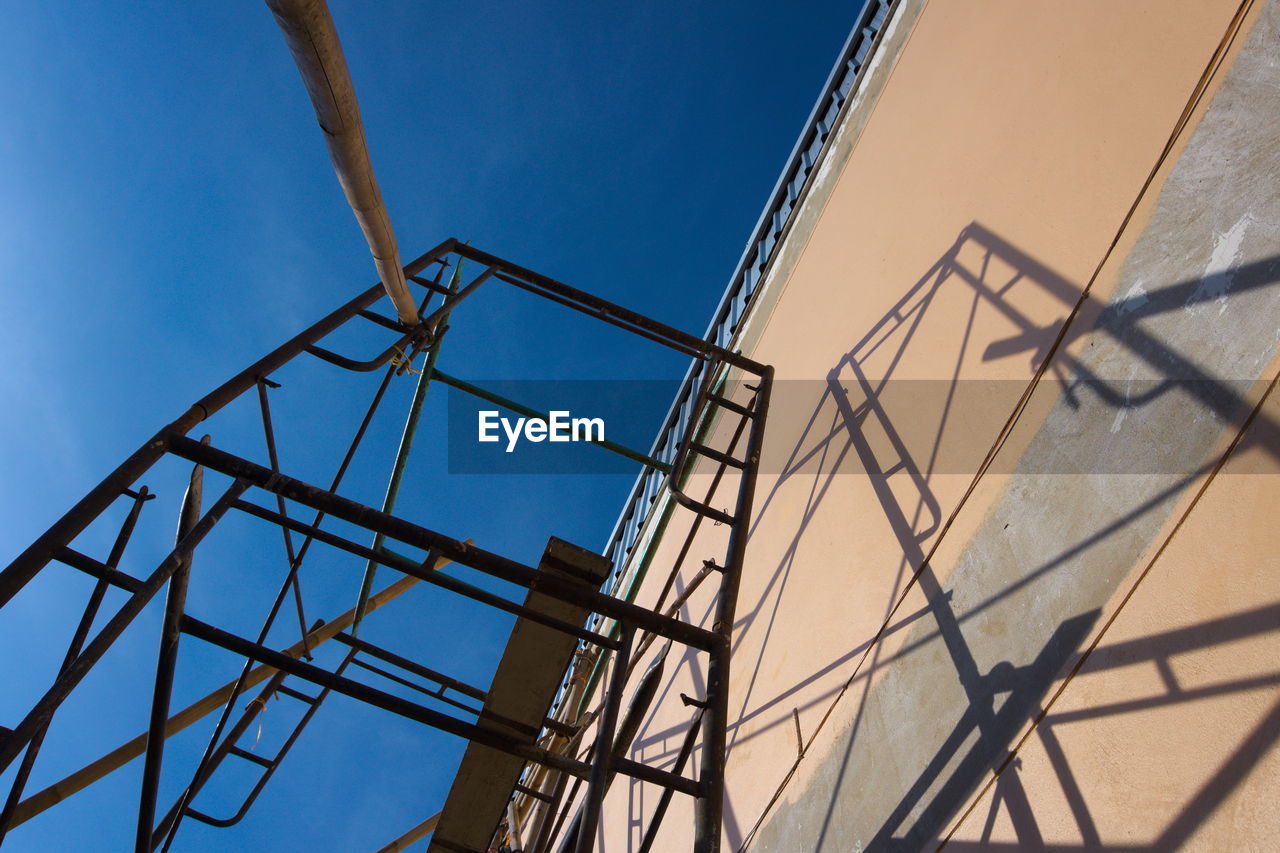 LOW ANGLE VIEW OF CRANE AGAINST BLUE SKY