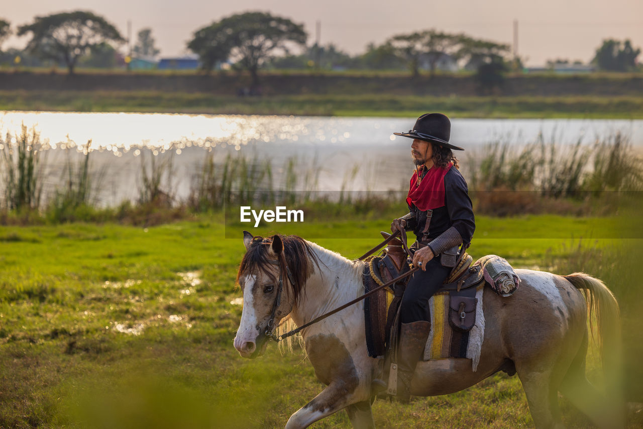 Cowboy's way of life include riding a horse around locales.