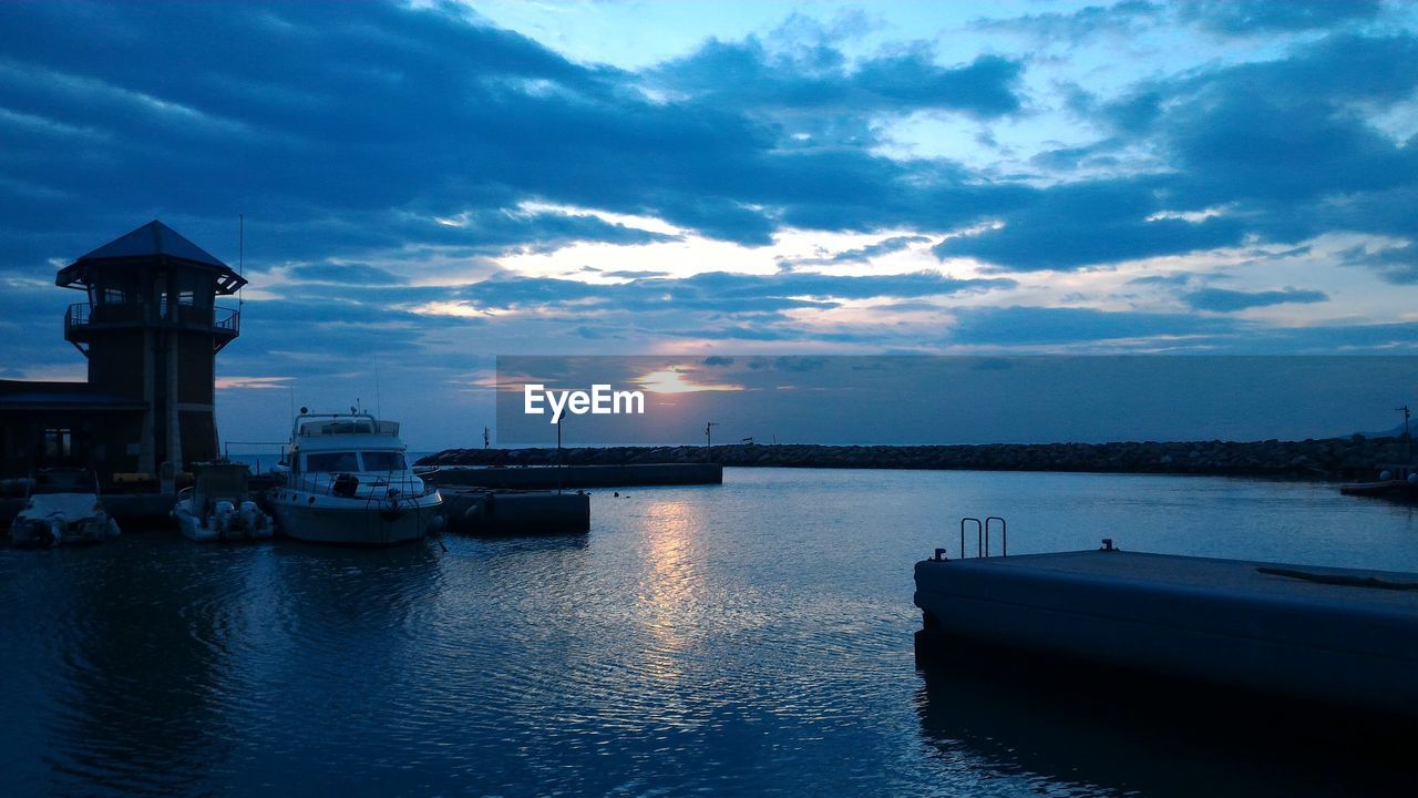 Boats in sea at sunset