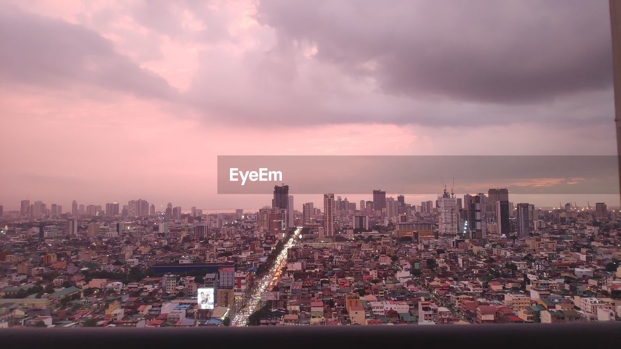 Aerial view of buildings in city against cloudy sky