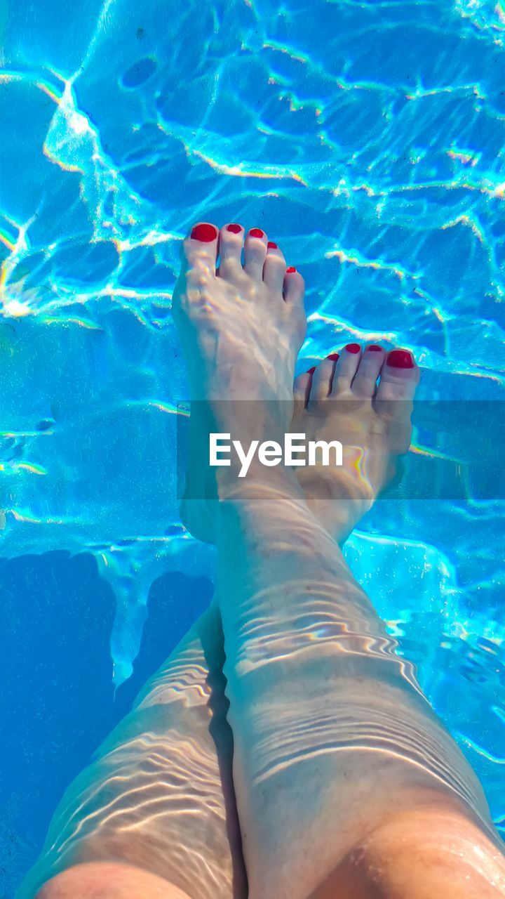 Low section of woman relaxing in swimming pool