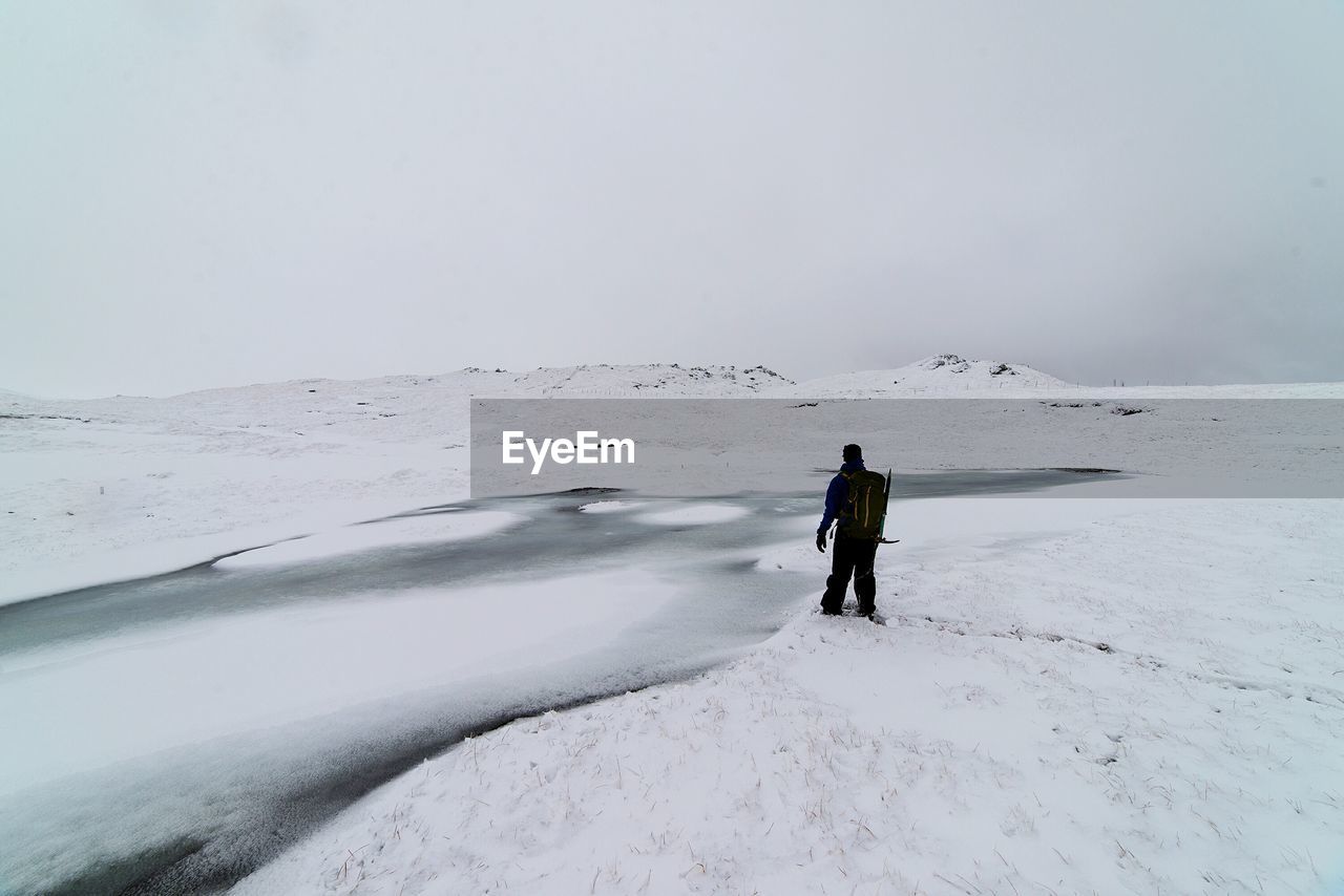 Rear view of man standing on snow covered field during winter