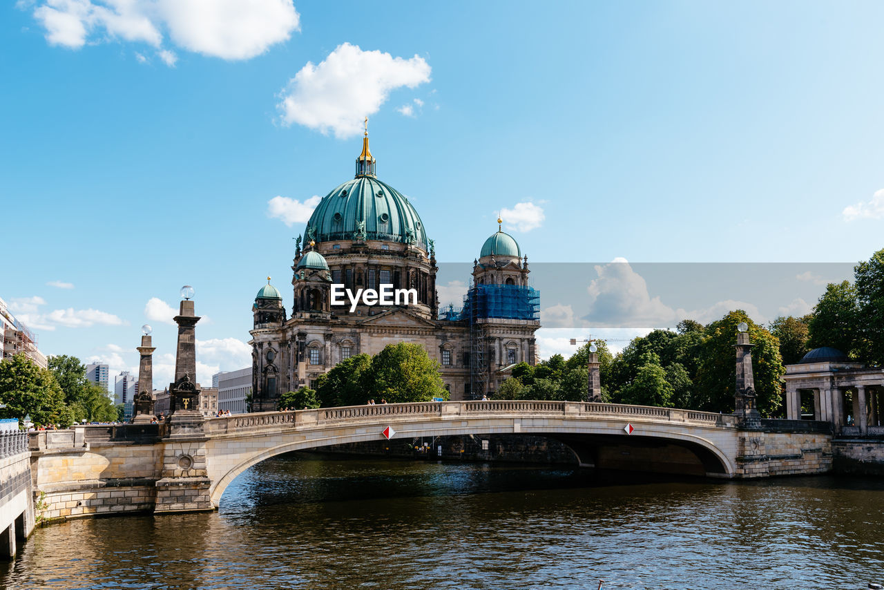 Arch bridge over river by building against sky. cityscape of berlin