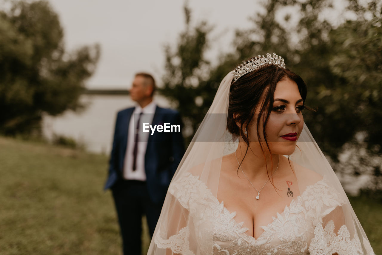 side view of bride holding bouquet against trees