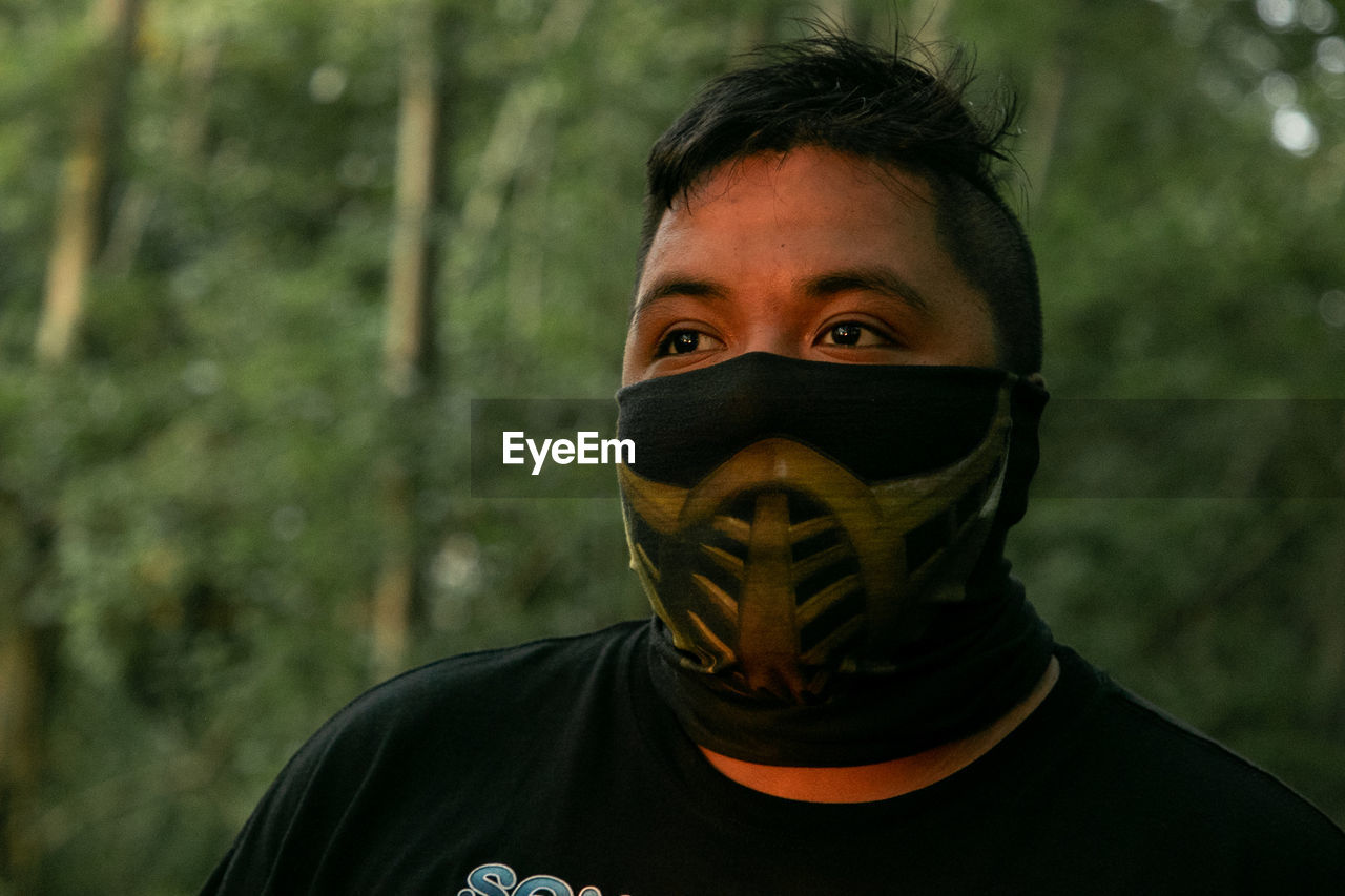Close-up of man wearing mask against trees