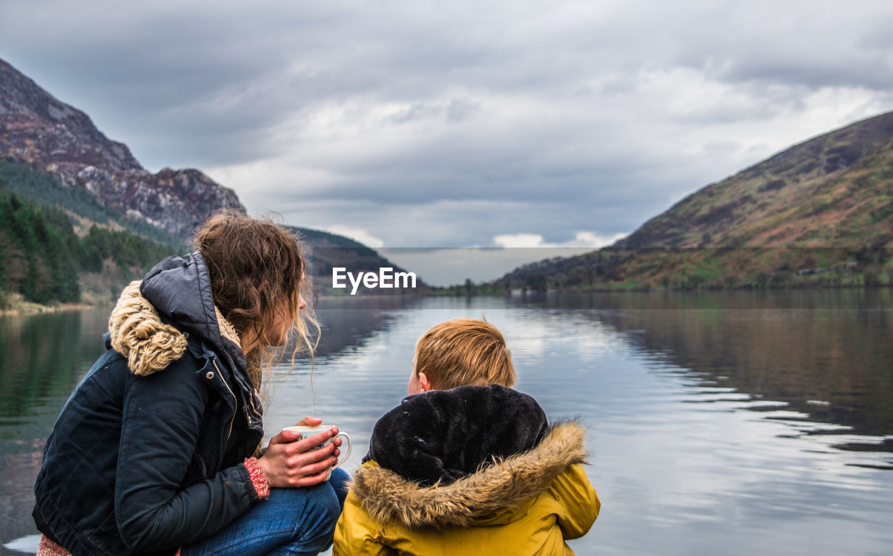 Woman and child by lake against mountain range