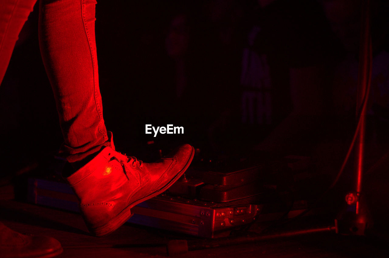 Low section of man standing on musical equipment on stage