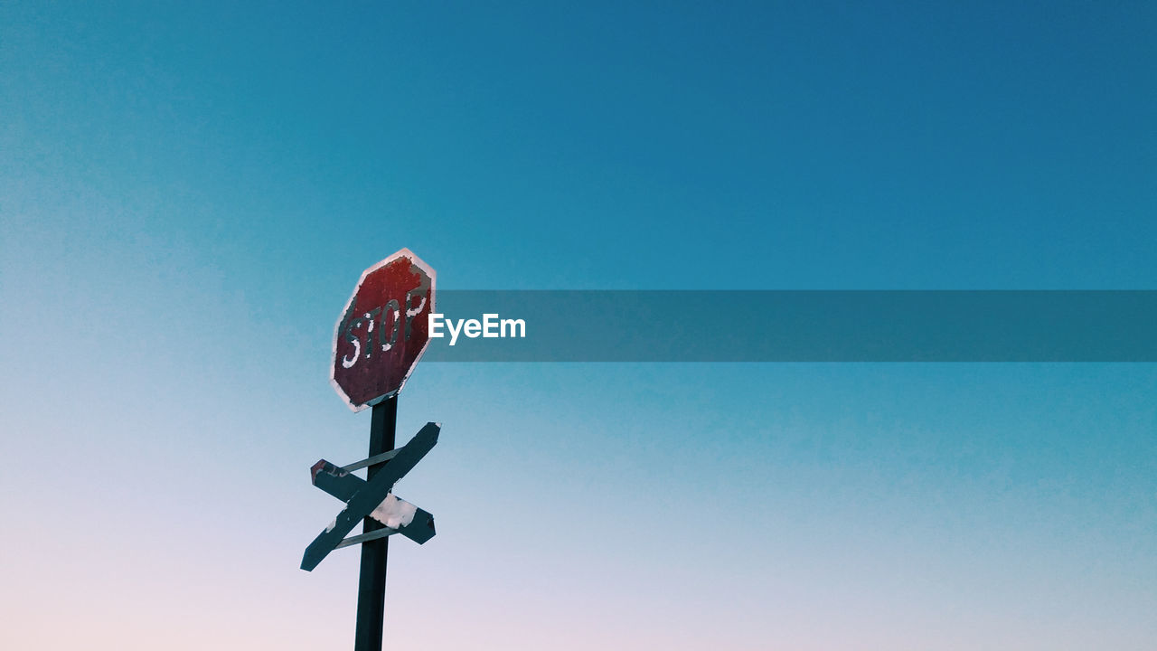 Low angle view of stop sign against clear blue sky