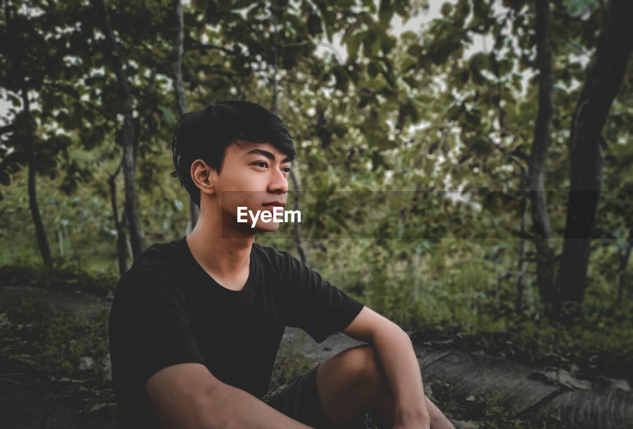 Young man looking away in forest