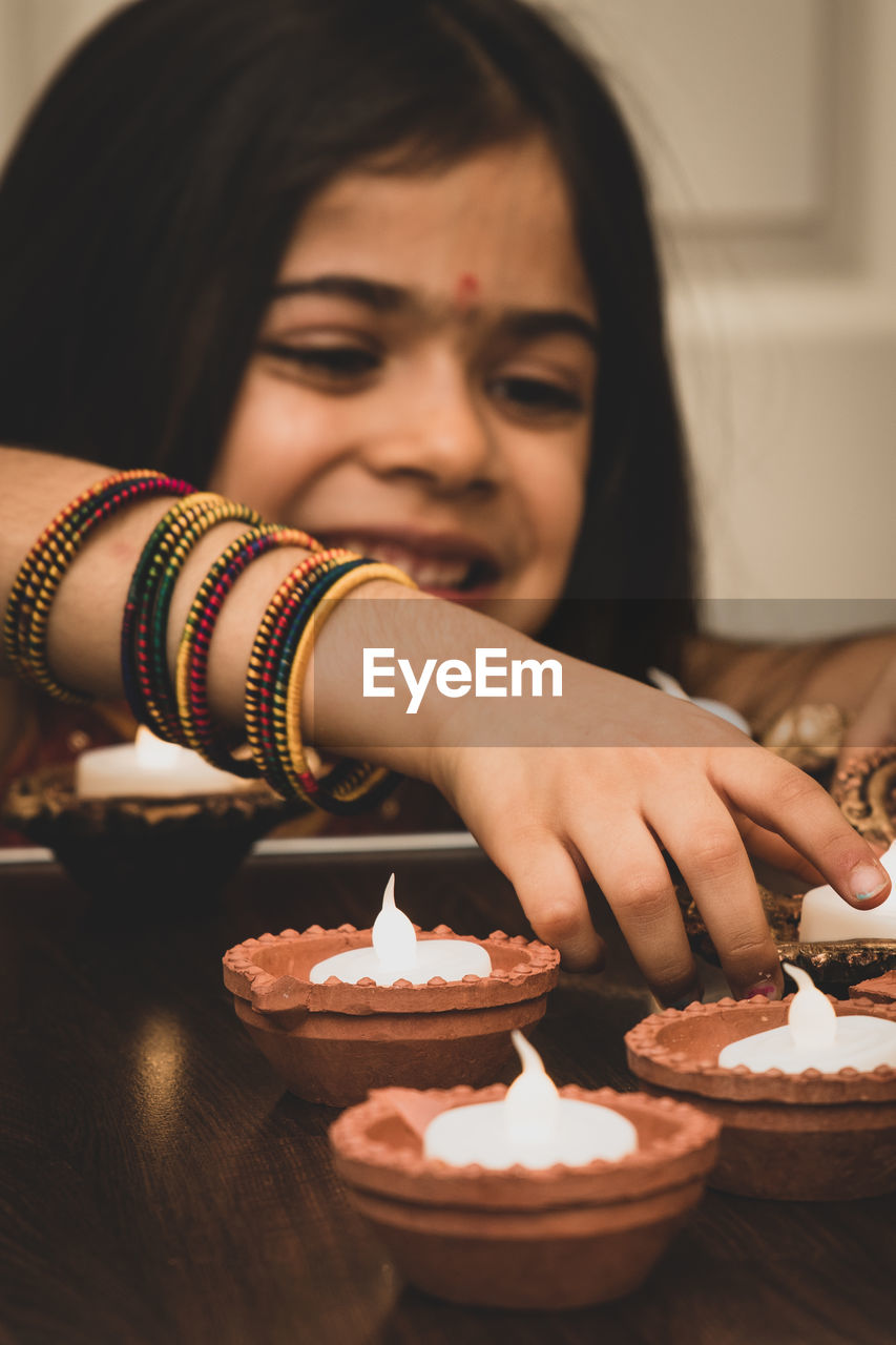 Smiling girl burning diya at home