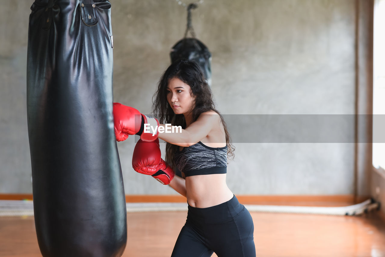 Young woman hitting punching bag in studio