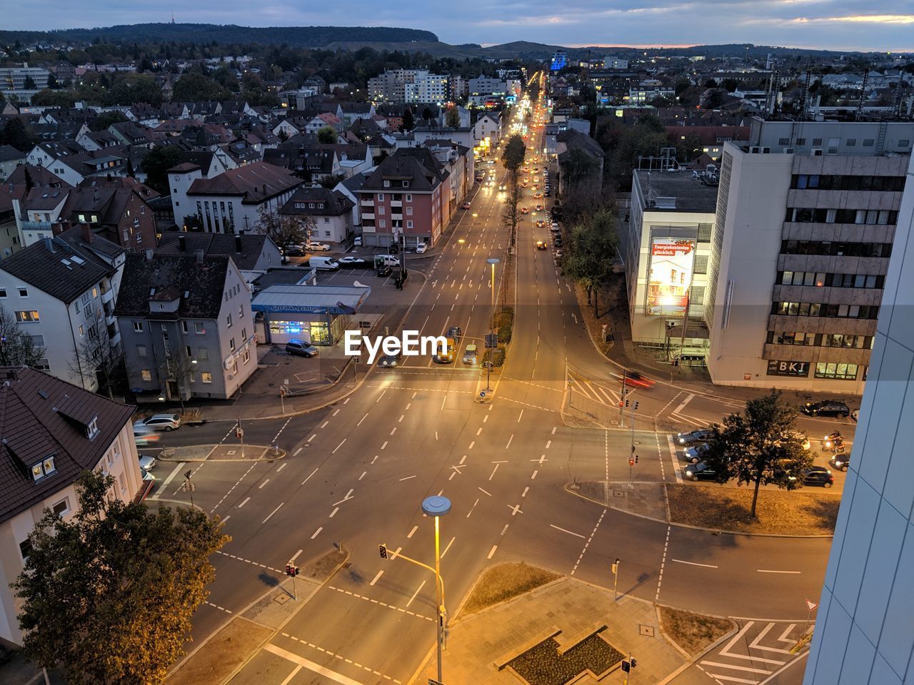 HIGH ANGLE VIEW OF ILLUMINATED CITY STREET AND BUILDINGS IN BACKGROUND