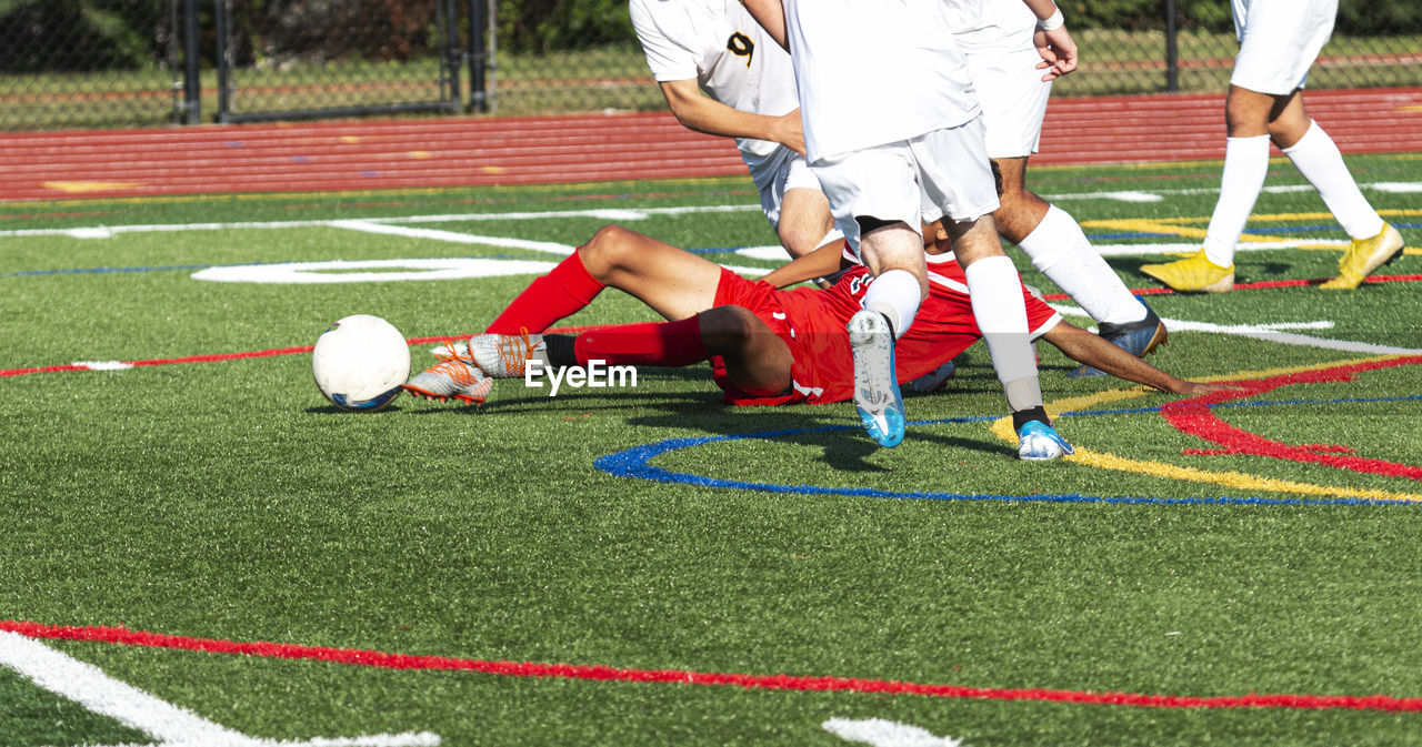 Low section of men playing soccer on field