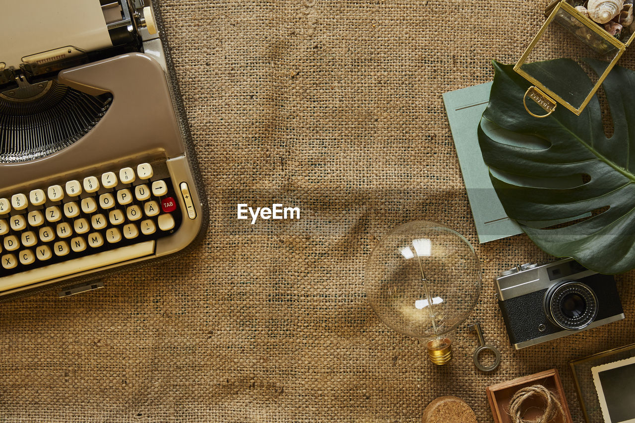 High angle view of light bulb with typewriter and camera on burlap