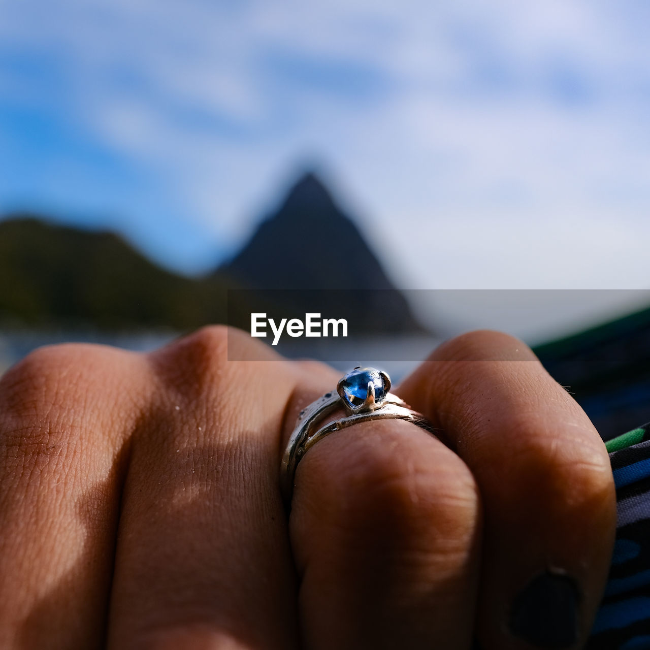 Cropped image of woman hand with ring against sky