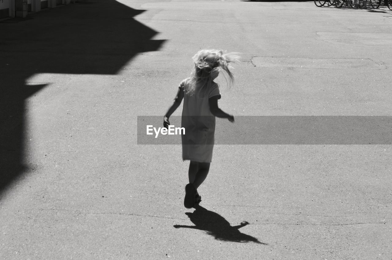 Rear view of girl walking on street in city