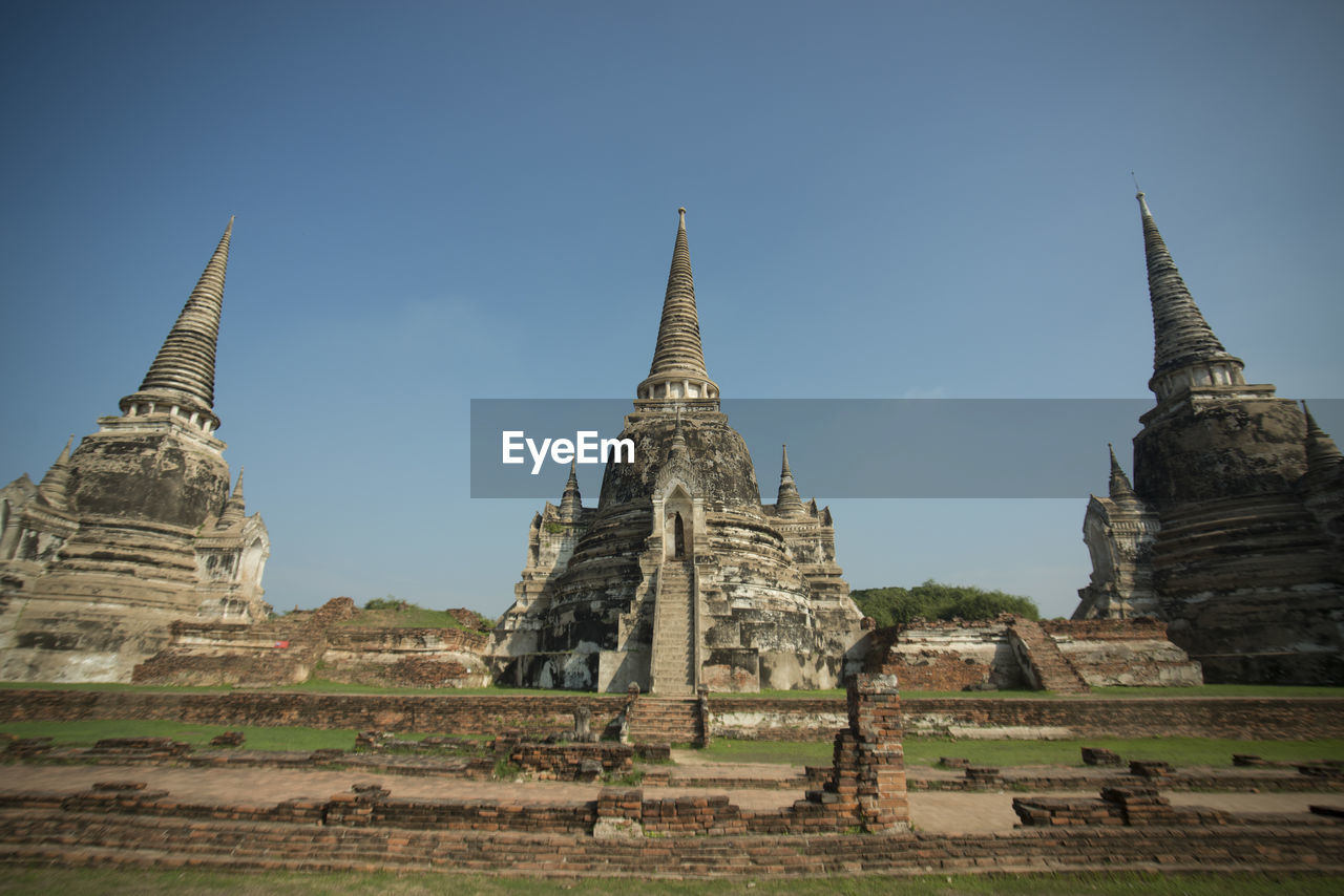 Low angle view of buddhist temple against clear blue sky