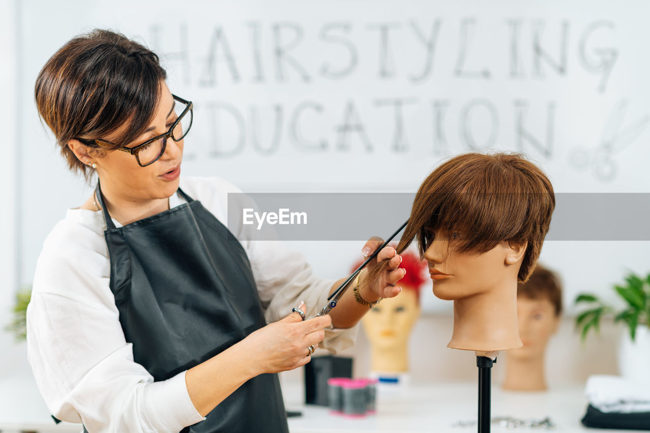 Haircutting education - hairstylist explaining haircutting techniques to students