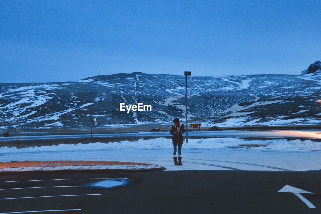 Woman standing on road against mountain during winter