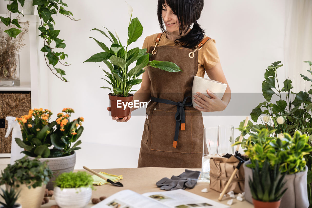 Female gardener holding potted plant, white peace lily