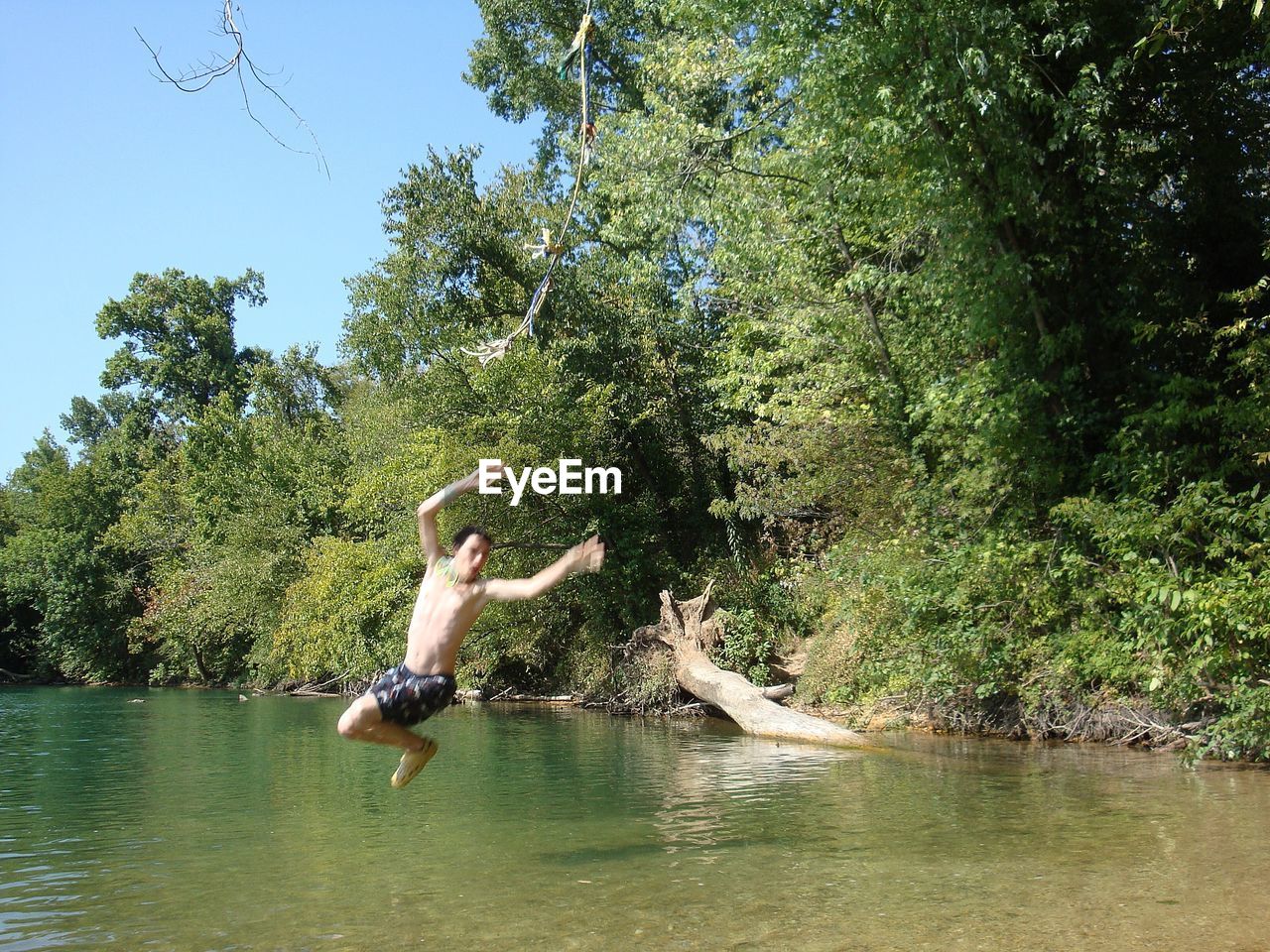Full length of shirtless man jumping in lake