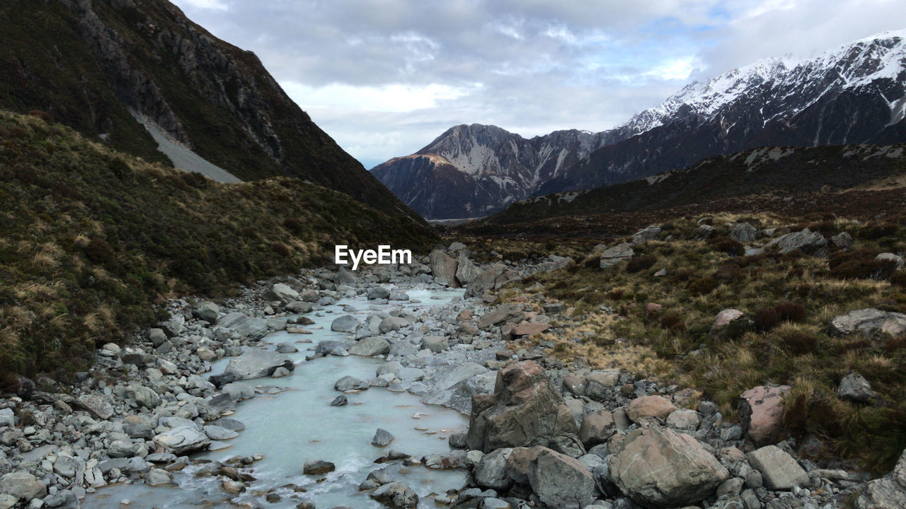 Scenic view of stream amidst mountains against sky