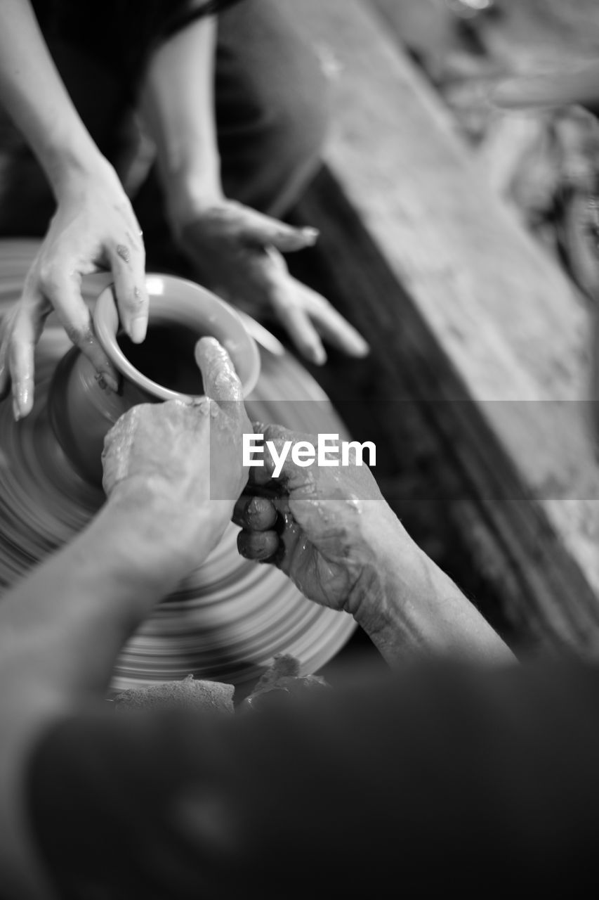 Midsection of people working on pottery wheel