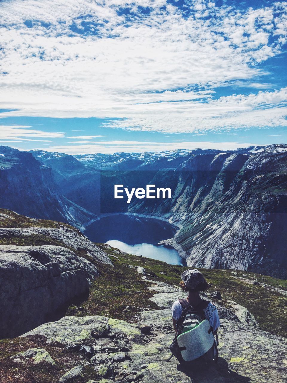 Rear view of woman sitting on mountain against sky