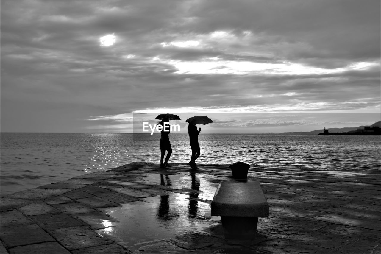 People standing on beach against sky