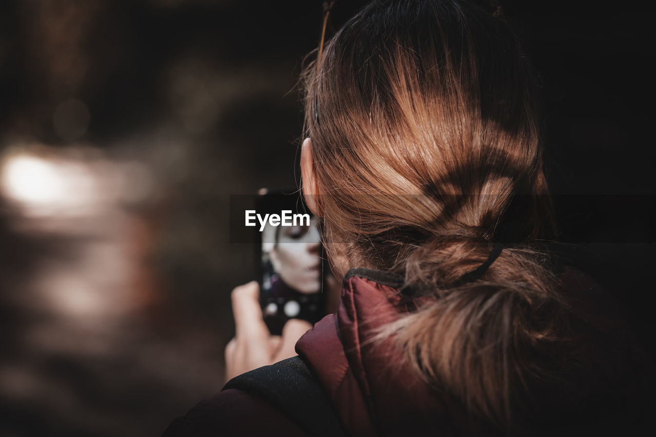 Rear view of woman photographing outdoors