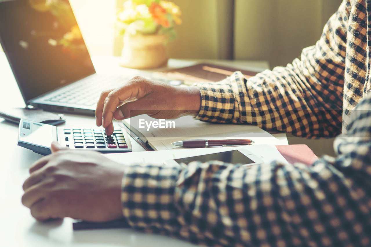 MIDSECTION OF MAN USING LAPTOP