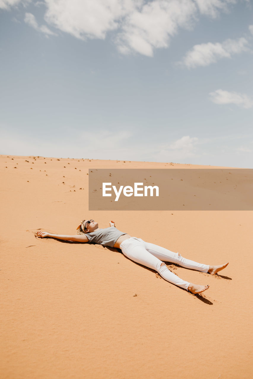 Woman lying down on desert in sunny day