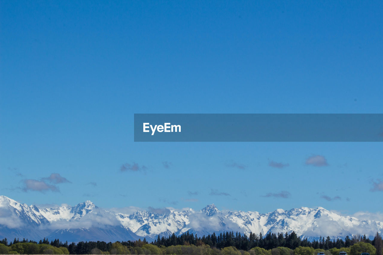 Scenic view of snowcapped mountains against clear blue sky