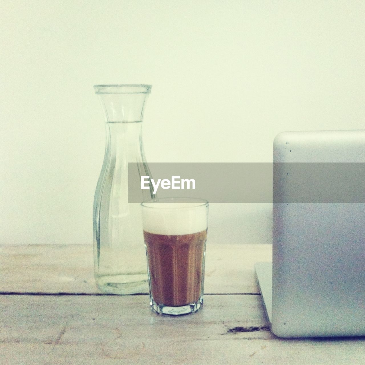 Close-up of glass jar with coffee and laptop