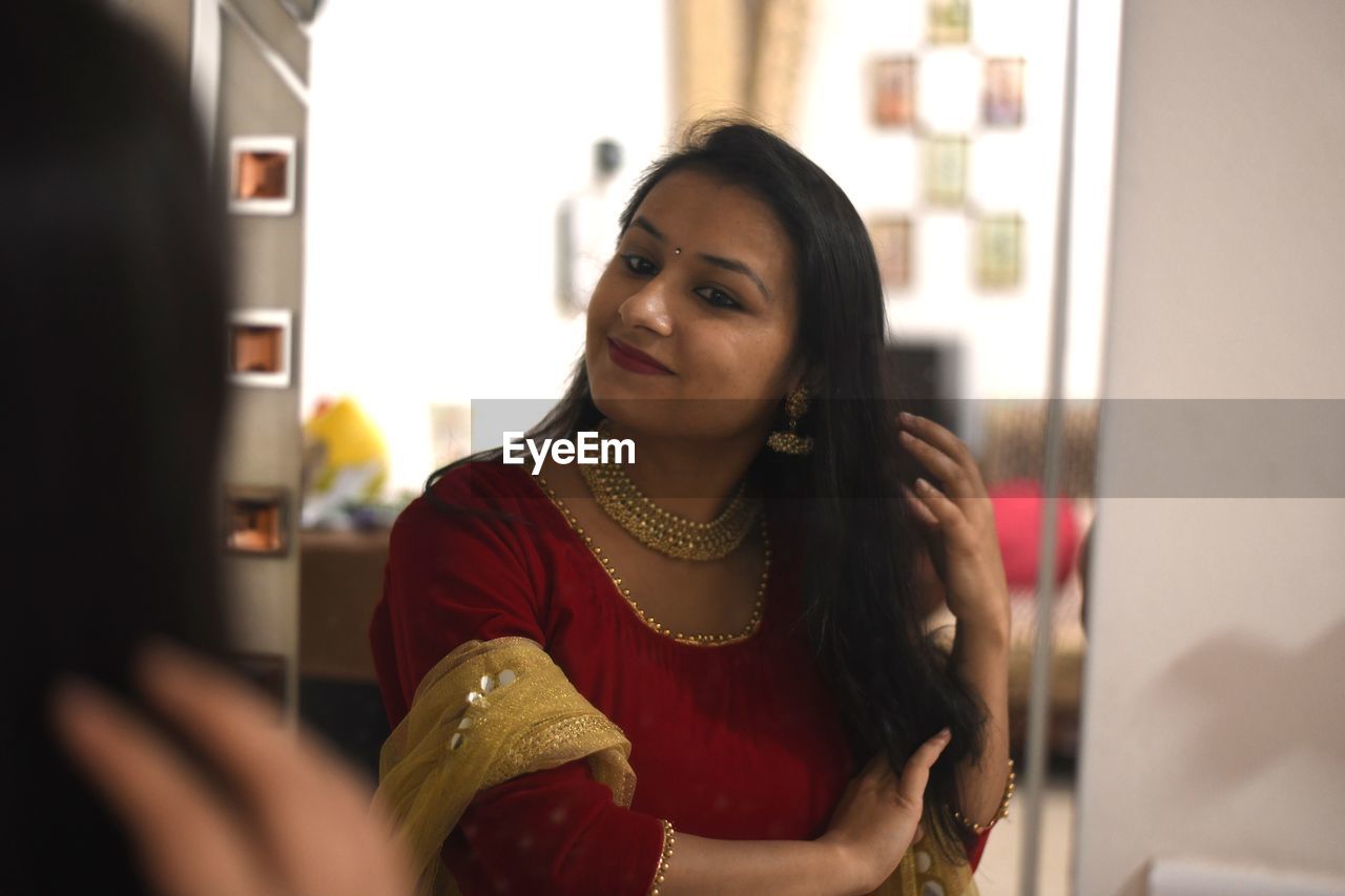 Smiling woman in traditional clothing standing in front of mirror