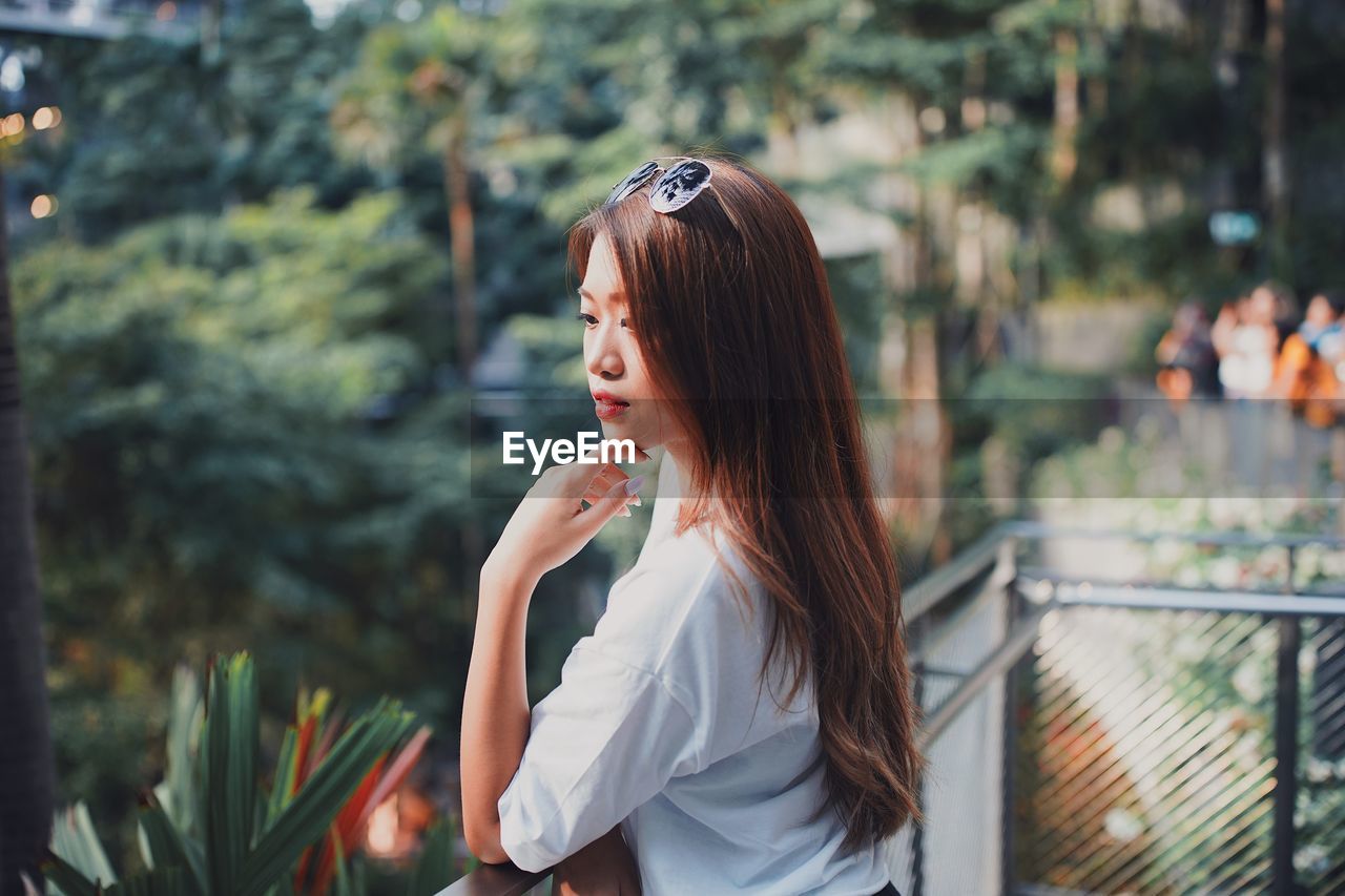 Young woman looking away while standing by railing