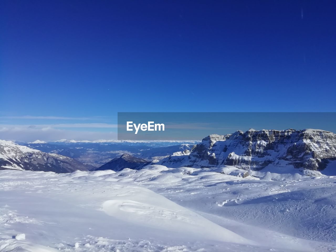 Scenic view of snowcapped mountains against clear blue sky